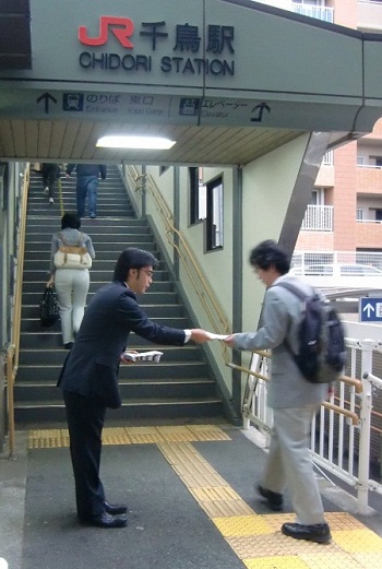 朝の駅立ちで県政報告を配布
