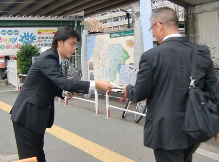 朝の駅立ちで県政報告を配布